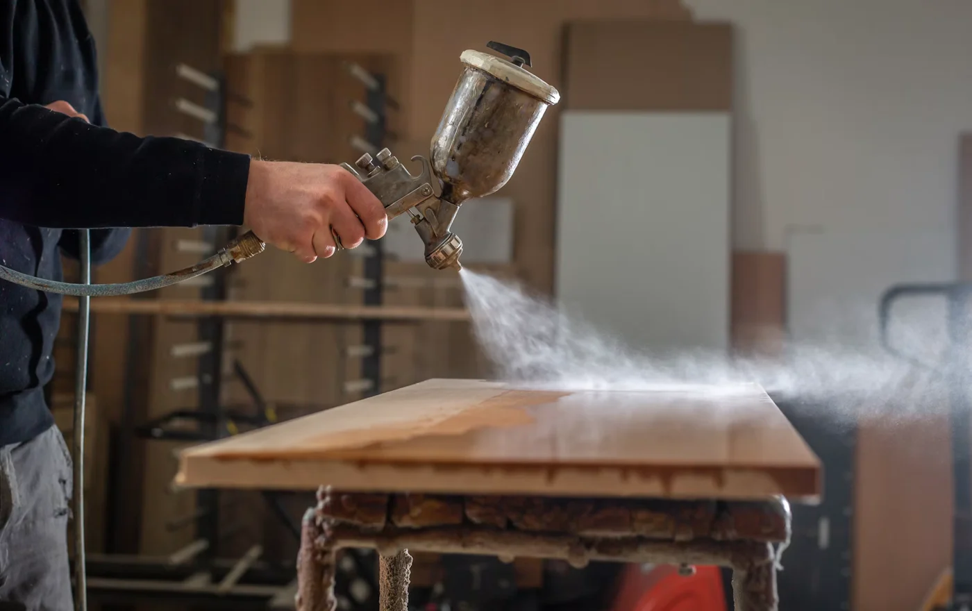 Dans un atelier, application d’une finition sur une pièce de bois